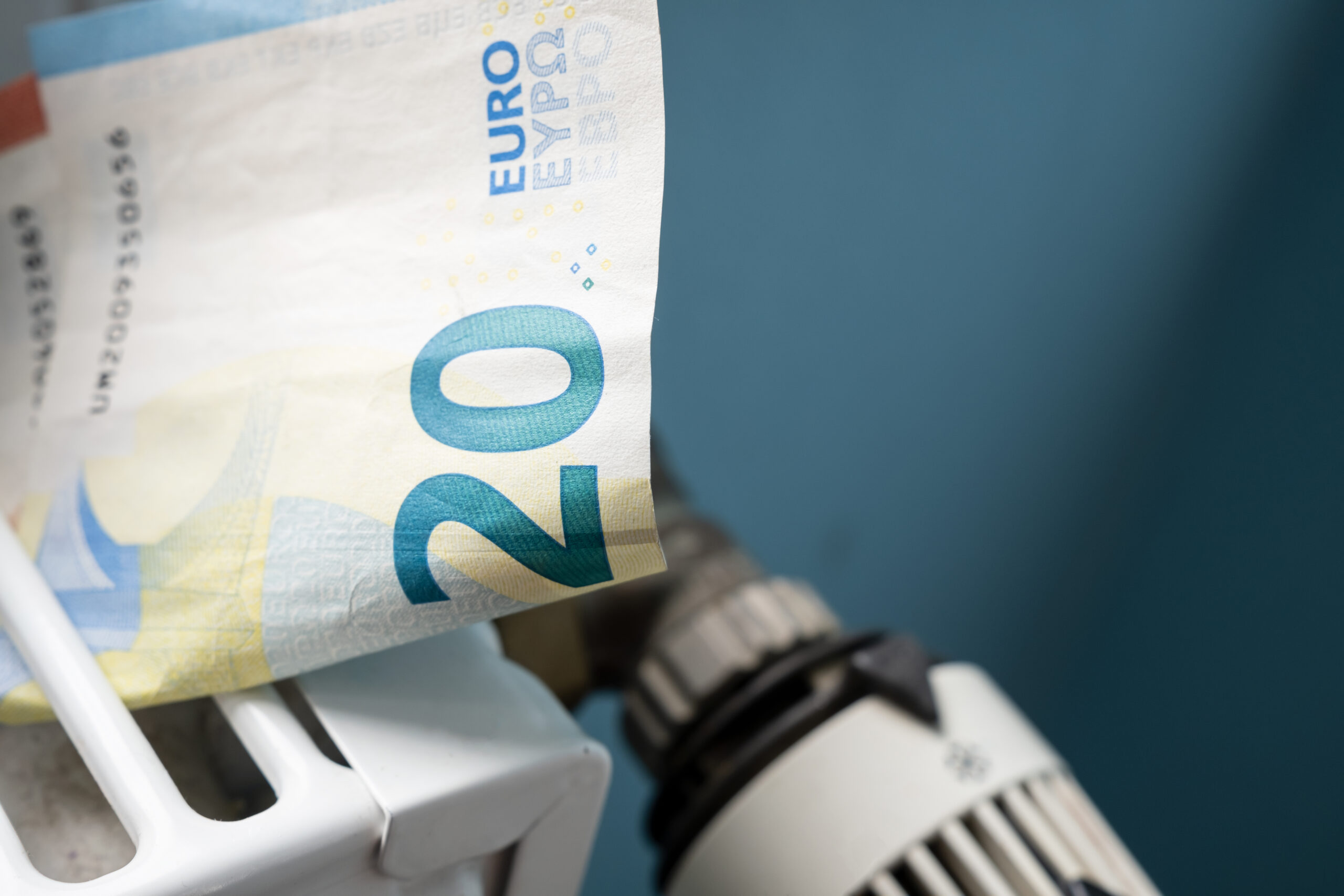 euro banknotes in a radiator and a thermostat knob at a minimum, close up. concept of energy crisis and expensive heating costs.