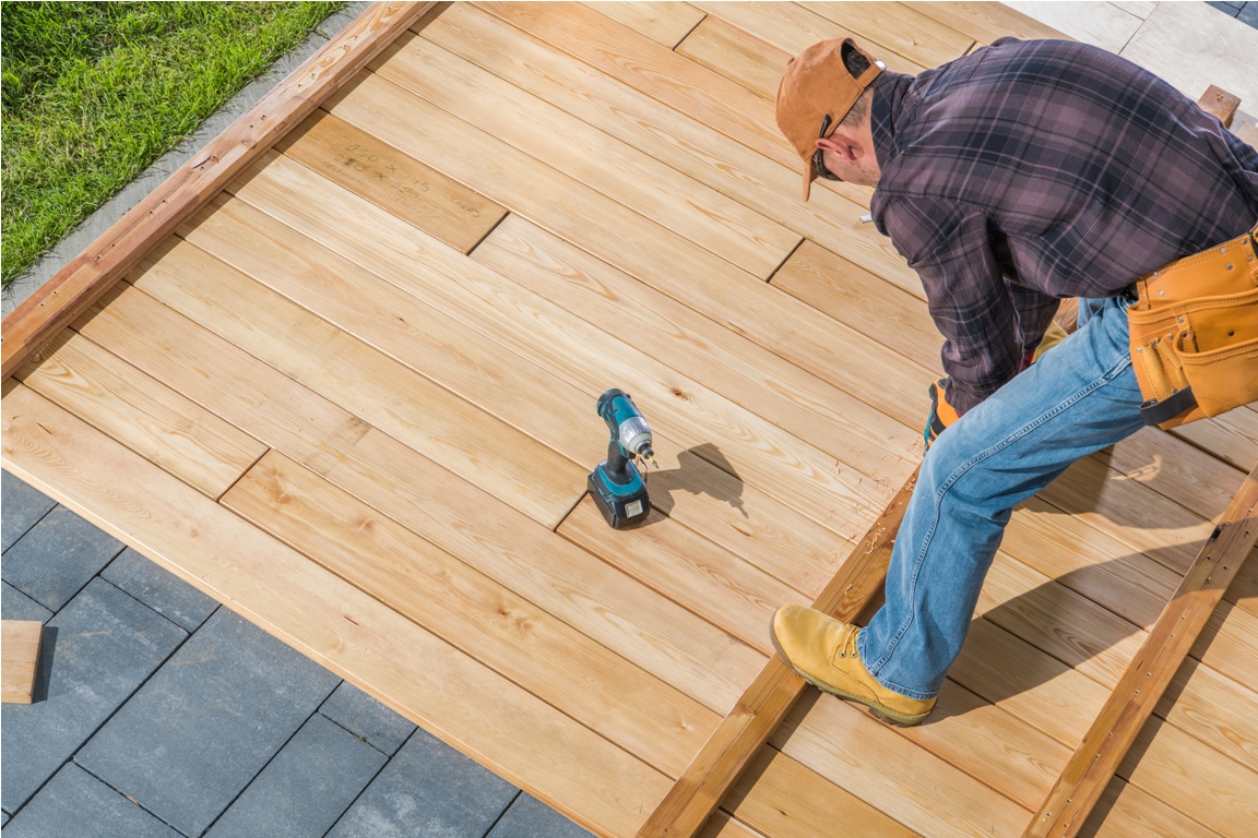 men building wooden deck on his backyard