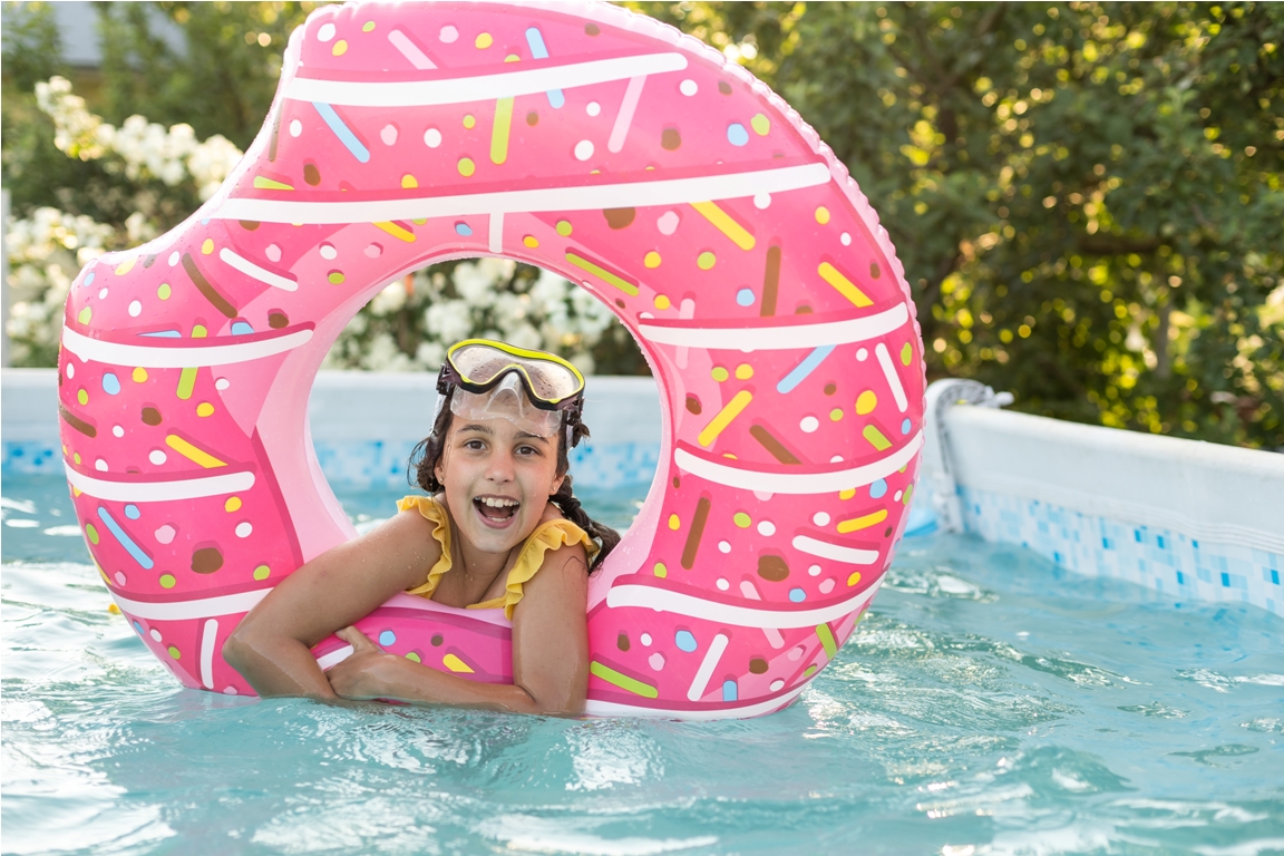 girl plays an inflatable ring is in swimming pool in the garden