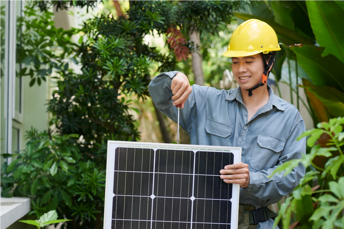 portrait of smiling solar panel installer wearing hardhat screwing solar panel