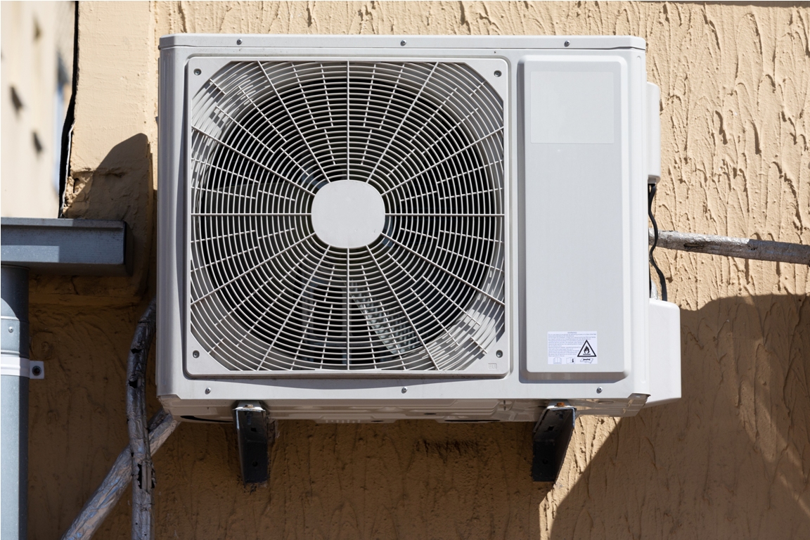 outdoor unit of a domestic air conditioner with a fan outside the building.