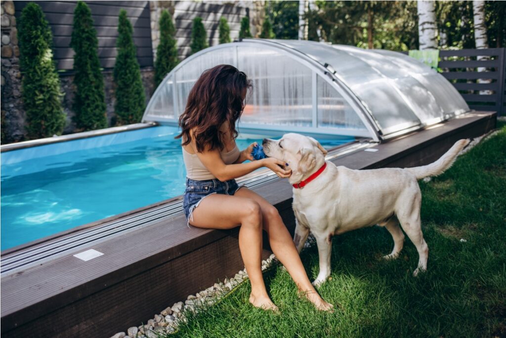 woman relaxing near swimming pool with cute dog.