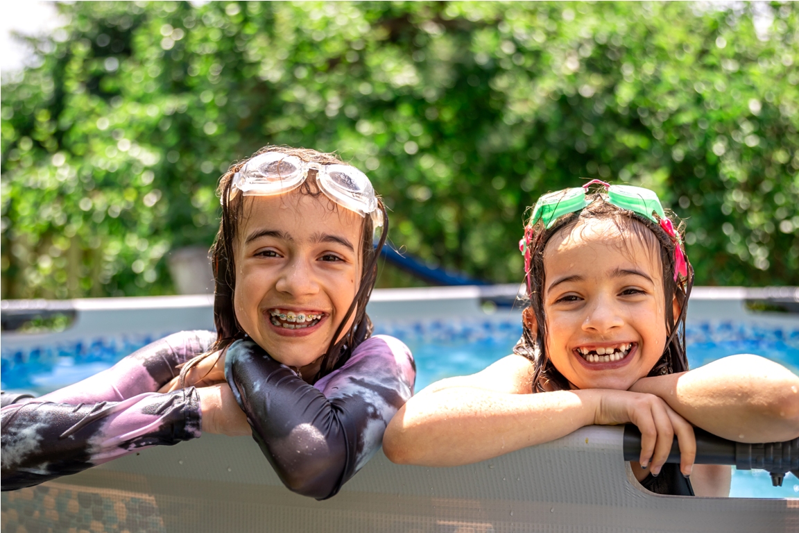 funny little girls in the pool in the backyard with swimming goggles.