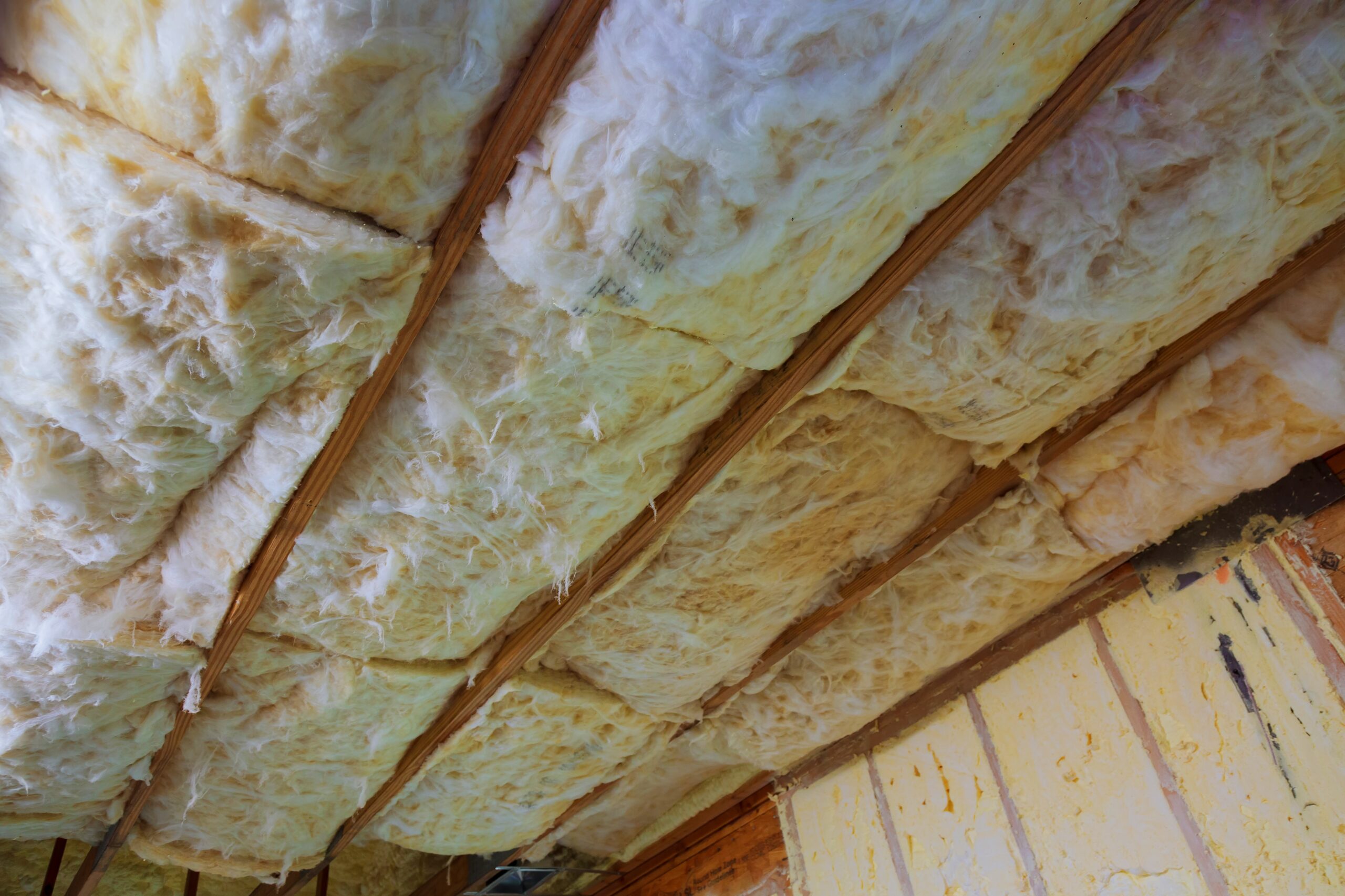 close up of strips of pink fiberglass insulation in a wall