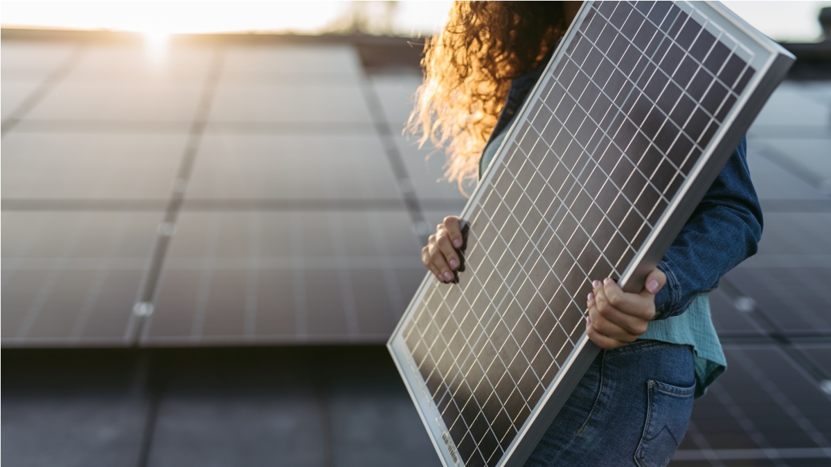 close up of a woman holding solar panel on the roof with photovoltaics panels.