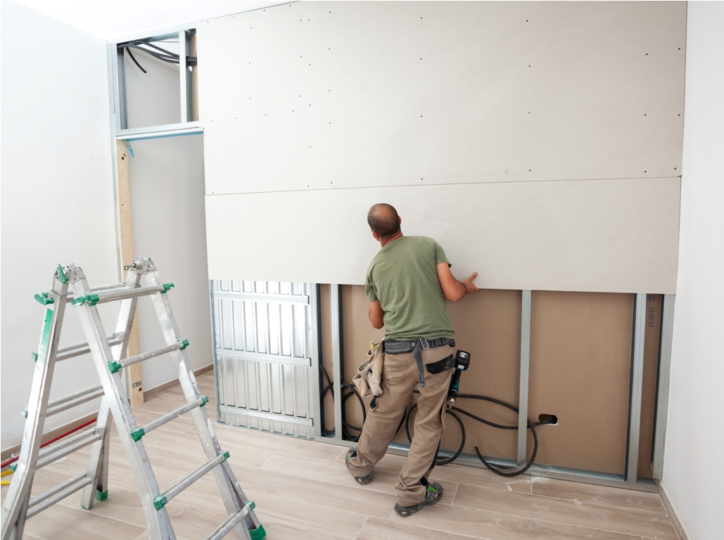worker building plasterboard wall.